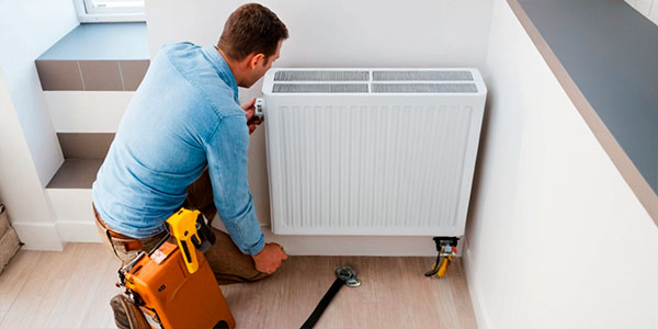 сантехник ремонтирует радиатор отопления